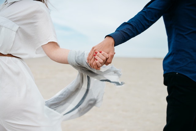 Article on Man and women holding hands on a beach